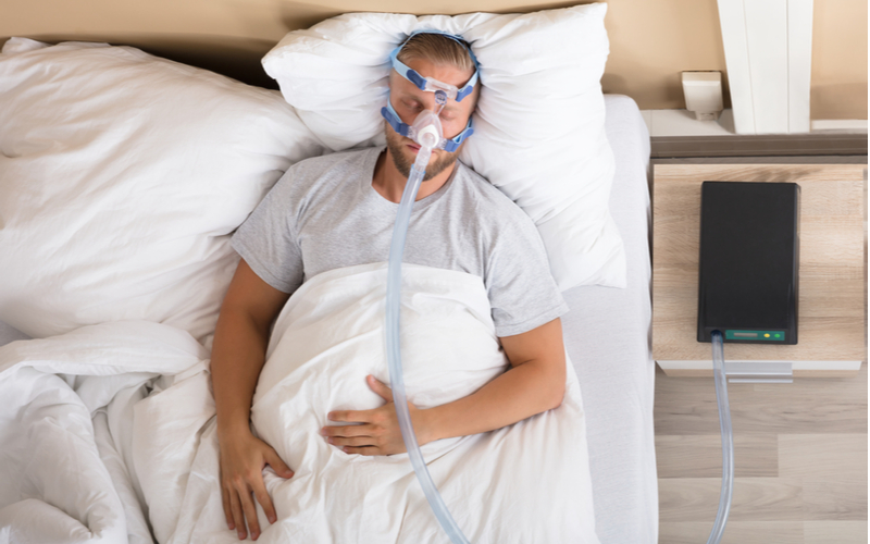 Man sleeping in bed with CPAP machine.
