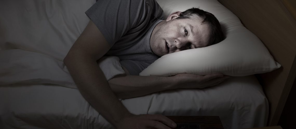 Man lying in bed unable to sleep