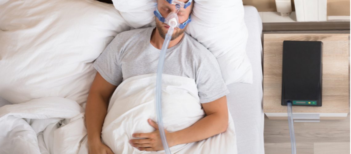 Man sleeping in bed with CPAP machine.